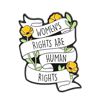 A white ribbon reading “Womens rights are human rights” wraps yellow flowers with green leaves on this bold enamel pin perfect for fans of feminist flair.