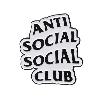 A black and white graphic enamel pin features the phrase ANTI SOCIAL SOCIAL CLUB in bold, overlapping letters with a playful, irregular arrangement.