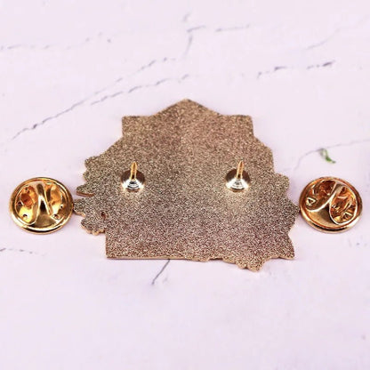 Yellow floral enamel pin features two butterfly clutch pin backs and is displayed from the reverse side on a light marbled background.