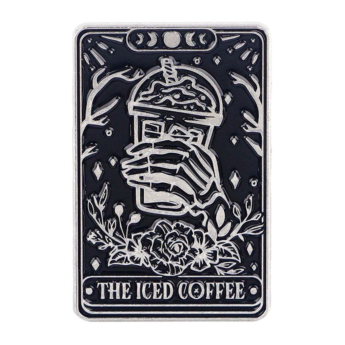 The Kiss Me Later rectangular enamel pin features a skeleton hand holding iced coffee, surrounded by flowers, branches, crystals, and three crescent moons above the words THE ICED COFFEE for a spooky vibe.