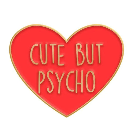 Red love heart enamel pin with a gold outline features CUTE BUT PSYCHO in bold gold letters—a playful accessory for anyone with attitude.