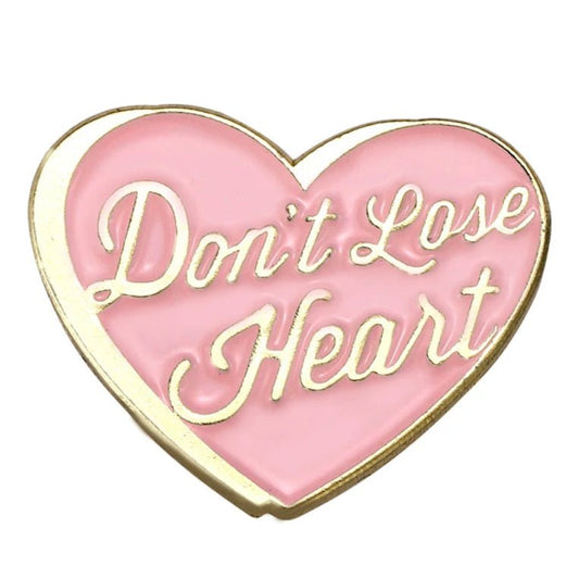 gold-trimmed pink heart enamel pin features “Don’t Lose Heart” in cursive gold lettering—a charming self-love reminder.