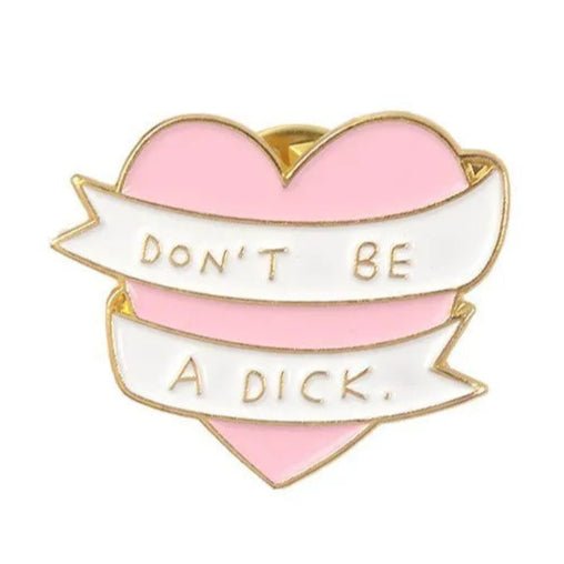 The My Cutesy Era enamel pin is heart-shaped and pink with gold edges, featuring a white banner that reads DONT BE A DICK in gold letters.