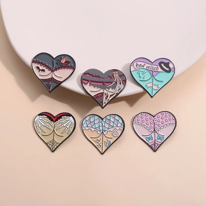 Six heart-shaped enamel pins in pastel and muted shades, featuring whimsical mermaid scales and subtle fishnet patterns, are arranged in two rows of three on a light beige surface.