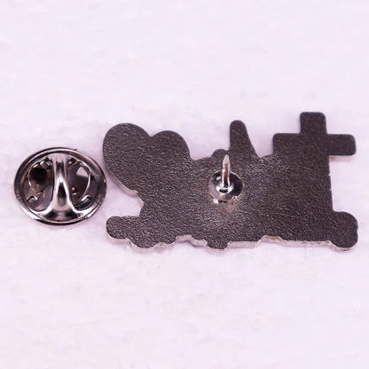 A Kiss Me Later metal train-shaped pin, similar to a Faith Hope Love badge, features a butterfly clutch backing. Displayed face down on a white surface with the backing removed.