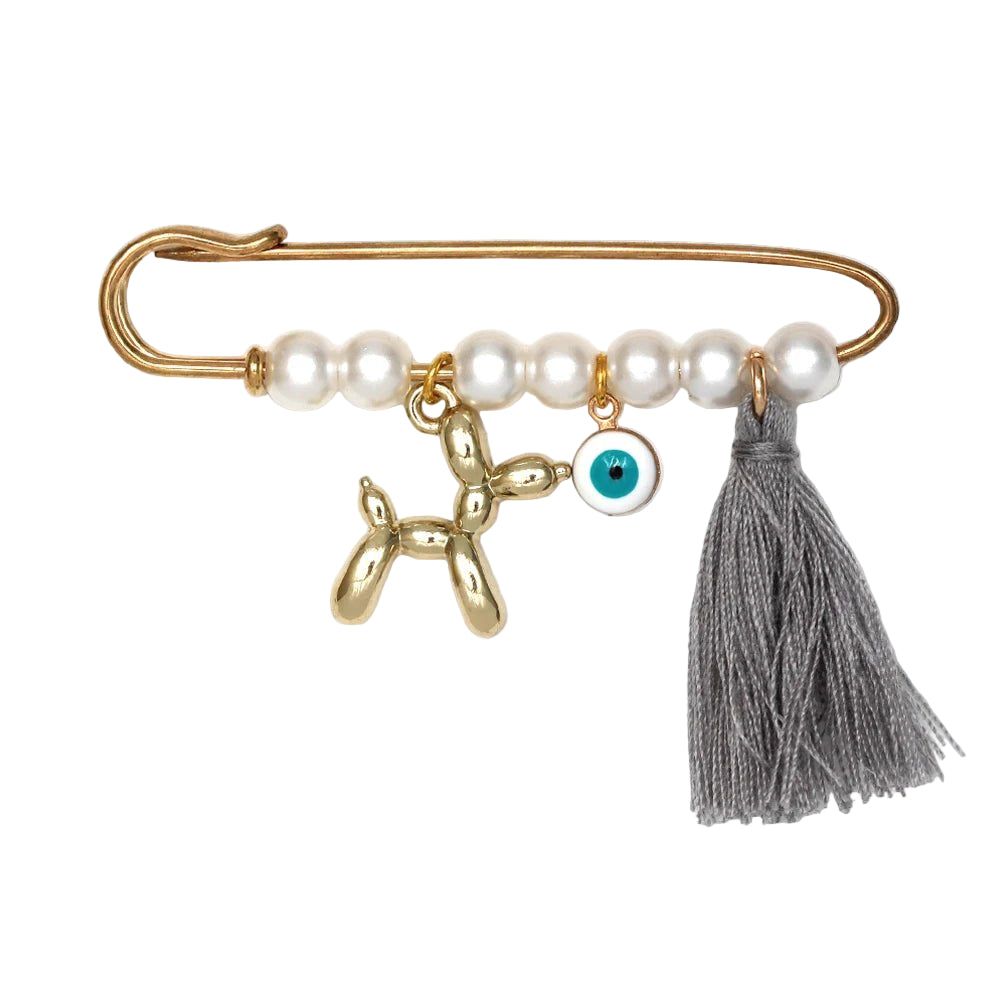 The Kiss Me Later brooch features a gold evil eye pin with white beads, a gold balloon dog charm, blue evil eye charm, and gray tassel—making it a unique baby shower gift.
