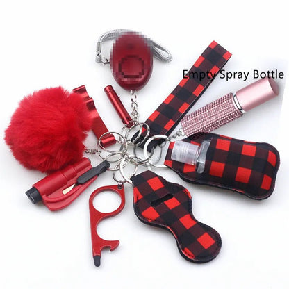 The Kiss Me Later red and black plaid keychain set includes a pom-pom, whistle, alarm, door opener tool, empty spray bottle, and lip balm holder—compact safety essentials for outdoor adventures.
