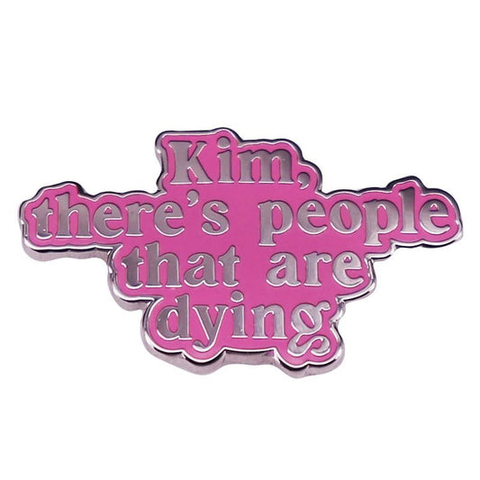 Enamel pin features “Kim, There’s People That Are Dying” in raised silver letters on pink and silver—a bold statement accessory for enamel pin fans.