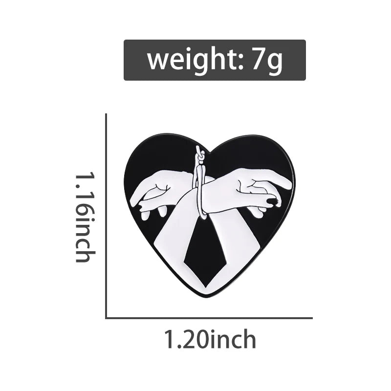 Kiss Me Later’s heart-shaped black and white enamel pin features two white hands bound at the wrists with rope. The Bound Hands pin measures 1.16 tall by 1.20 wide, weighs 7g, with weight shown above the pin.