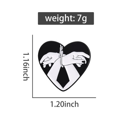 Kiss Me Later’s heart-shaped black and white enamel pin features two white hands bound at the wrists with rope. The Bound Hands pin measures 1.16 tall by 1.20 wide, weighs 7g, with weight shown above the pin.