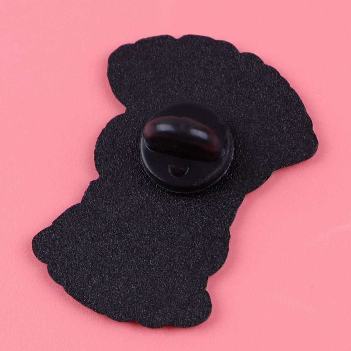 A black pin backing with a butterfly clutch is displayed on a pink surface, showing the rear side of the Menace To Society enamel pin.