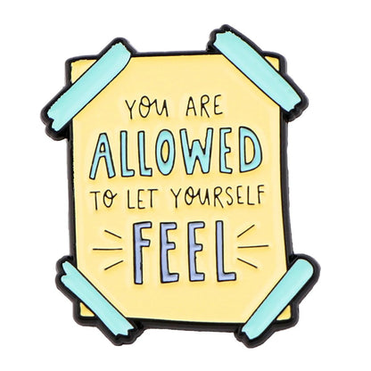 A yellow note taped at four corners with teal tape, reads “You are allowed to let yourself feel” in hand-drawn black and teal lettering—a gentle reminder of self-empowerment and mental health.