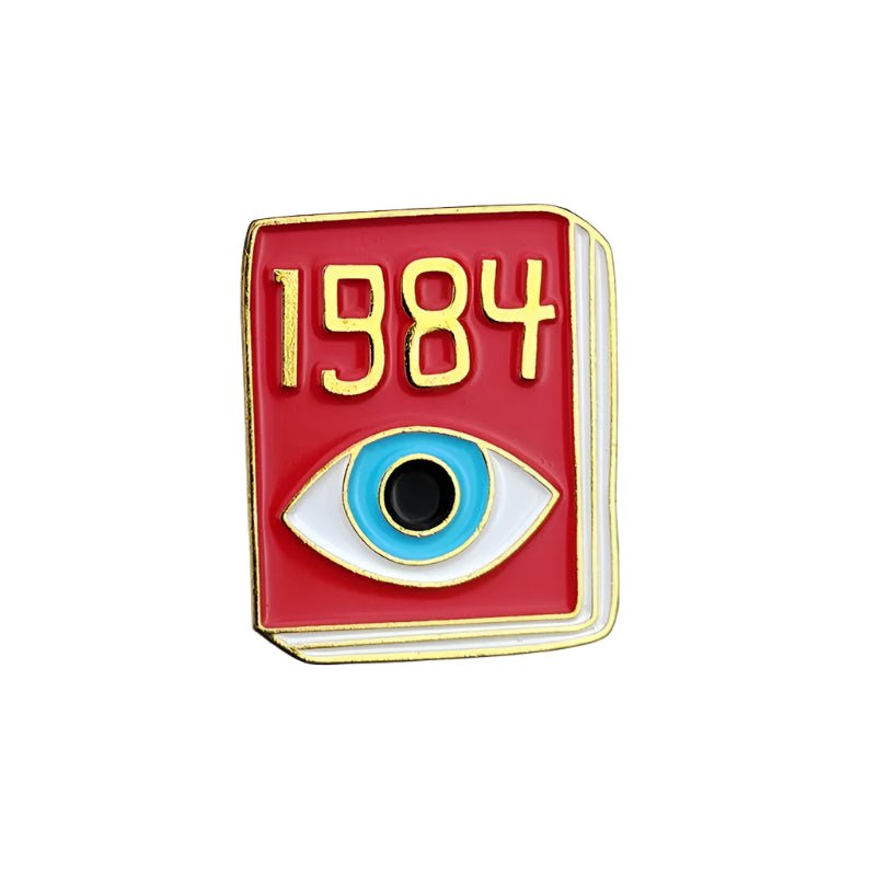 A red enamel pin by My Cutesy Era shaped like a book, featuring 1984 in gold and a blue-and-black eye—this accessory channels Breaking News vibes while nodding to George Orwell’s classic novel.