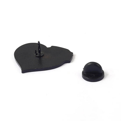 A black heart-shaped enamel pin with two pointed posts is displayed beside a black rubber pin backing on a white surface, ideal for pairing with your favorite Skeleton holding pink rose or pink milk carton enamel pin.