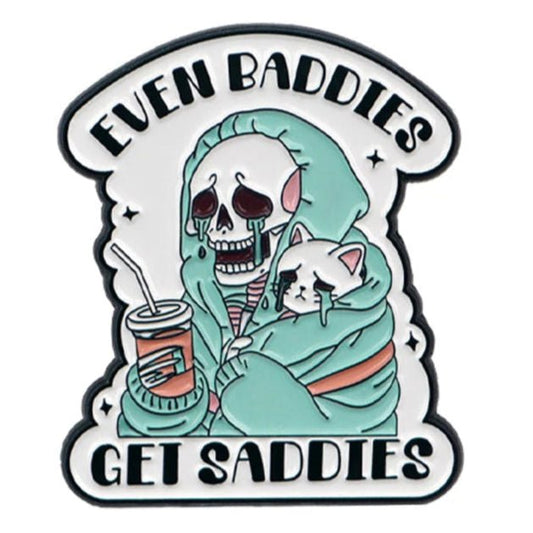 A cartoon skeleton in a teal hoodie and a sad white cat, both with tears and quirky cat pins. Bold text above and below says “EVEN BADDIES GET SADDIES.” 