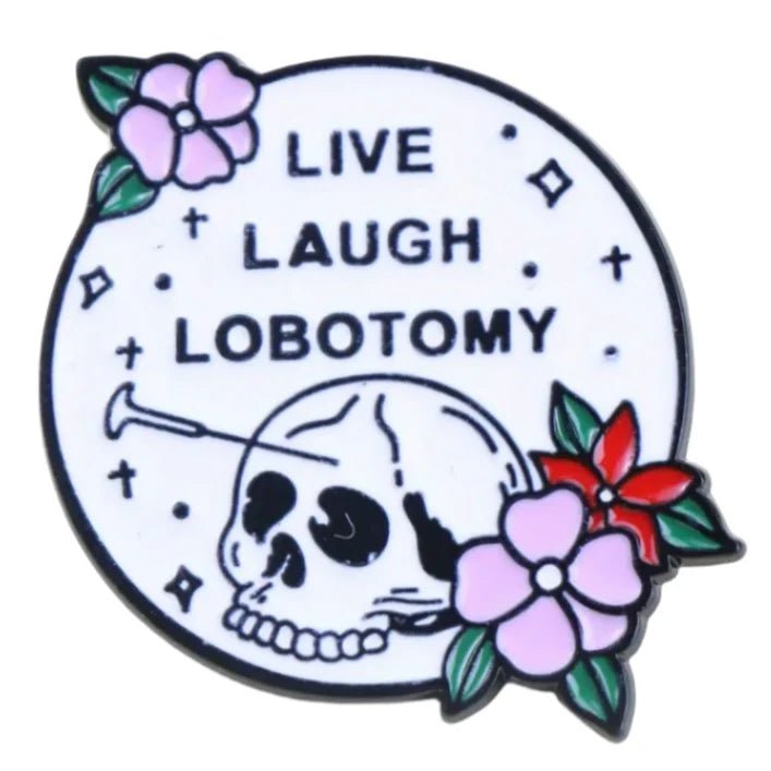 The Kiss Me Later enamel pin is circular with a skull, lobotomy tool, pink and red flowers, diamond sparkles, and “LIVE LAUGH LOBOTOMY” text on a white background—a bold accessory for your collection.