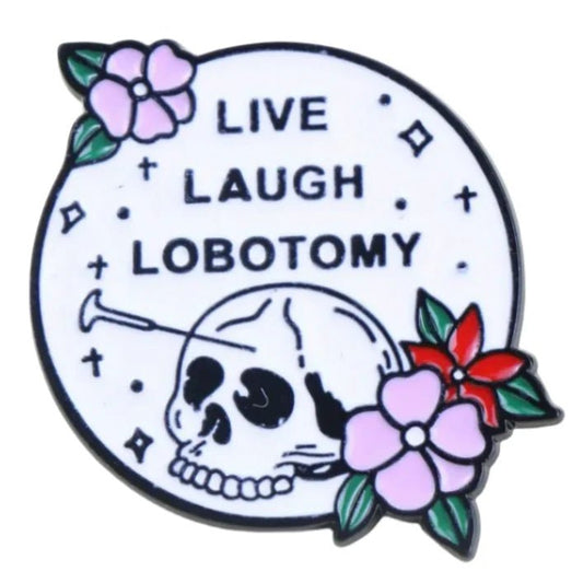 The Kiss Me Later enamel pin is circular with a skull, lobotomy tool, pink and red flowers, diamond sparkles, and “LIVE LAUGH LOBOTOMY” text on a white background—a bold accessory for your collection.