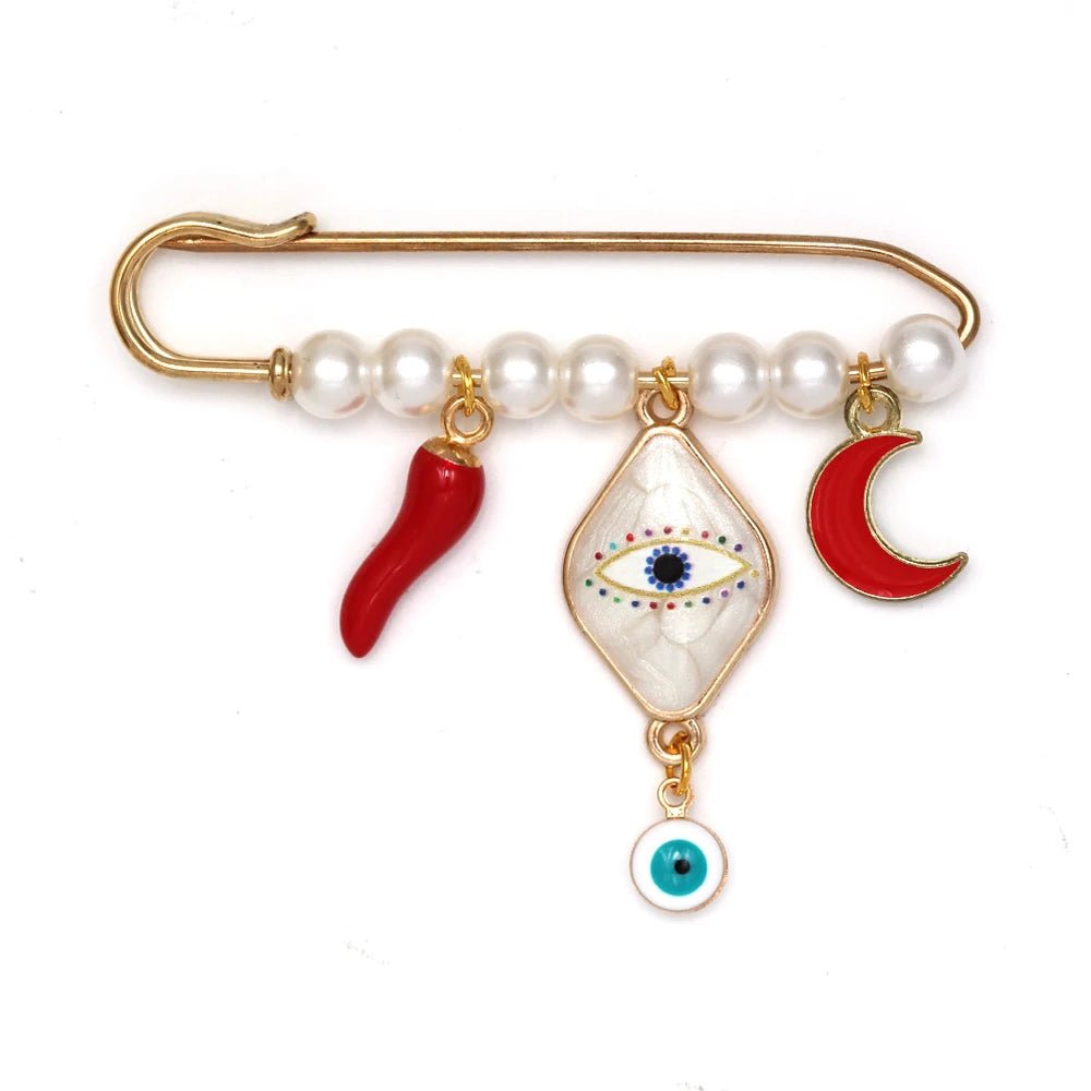The Kiss Me Later gold evil eye pin with white beads features three hanging charms—a red chili pepper, a blue diamond-shaped evil eye, and a red crescent moon—making it a perfect unique baby shower gift.