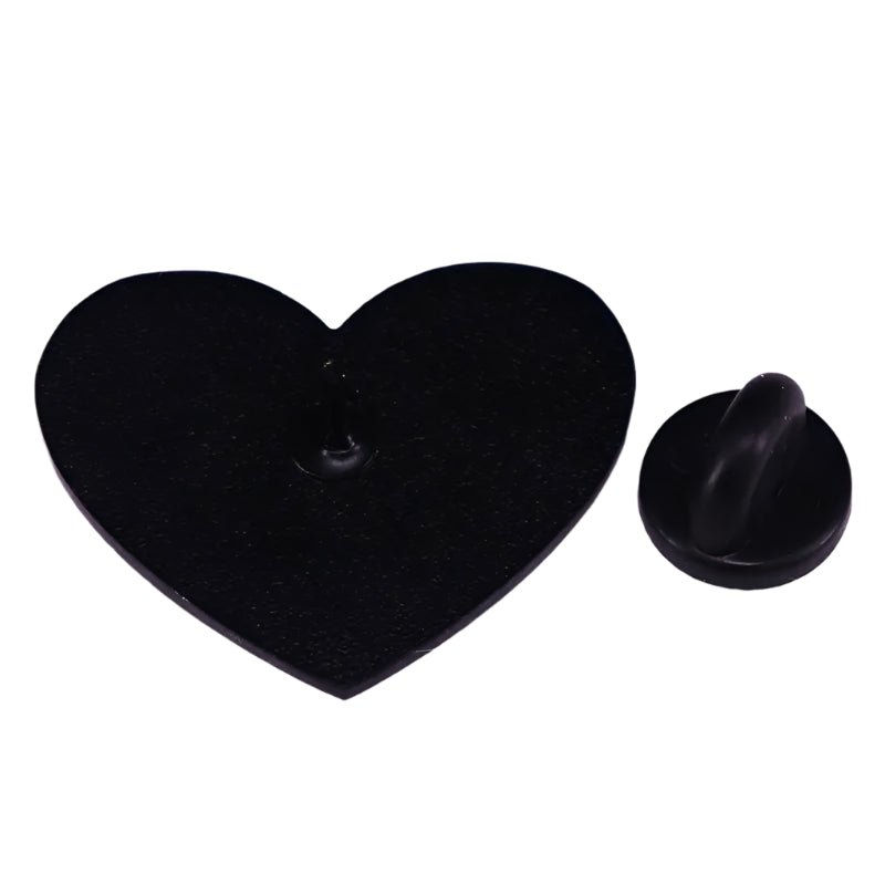 A  black heart enamel pin, shaped like a heart, is displayed next to its small peg and matching round piece on a white background.
