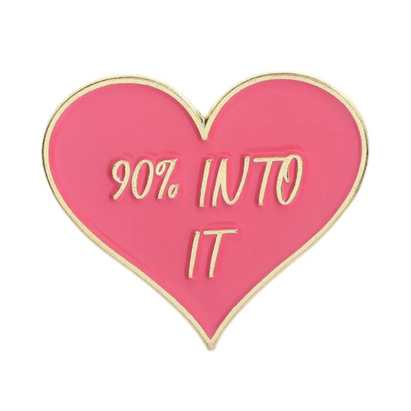 Red heart-shaped pin with gold edges and 90% INTO IT in gold lettering, crafted in the style of red and gold enamel pins.