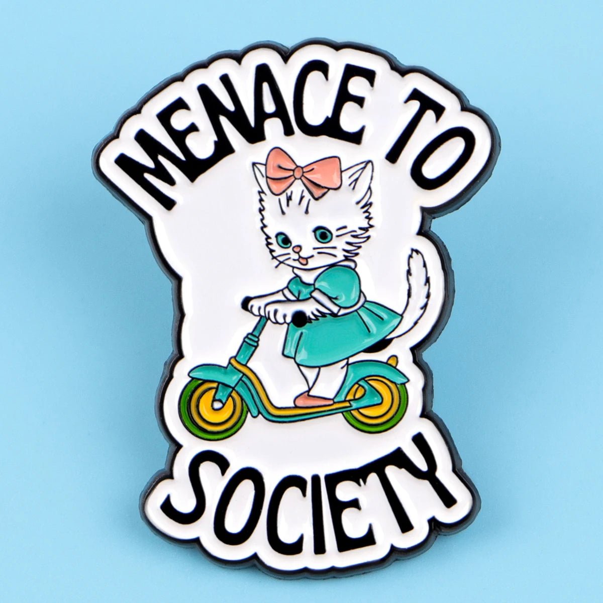 Add playful charm to your collection with a cat enamel pin, featuring a white kitten in a teal dress and pink bow riding a scooter, plus “Menace to Society” boldly printed above and below the design.