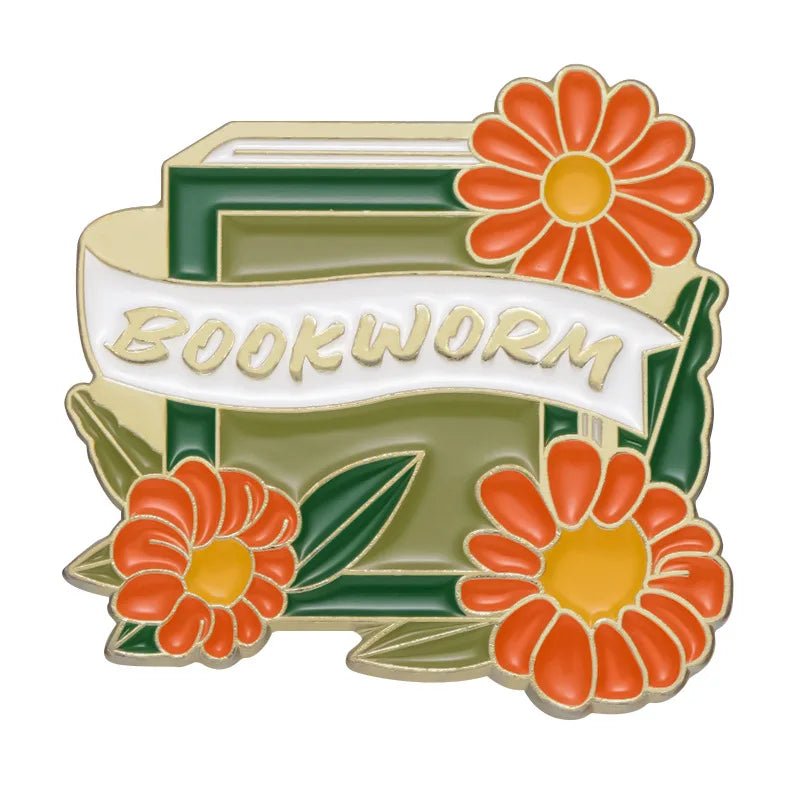 My Cutesy Era’s decorative book pin features an open green book with orange and yellow flowers, green leaves, and a “BOOKWORM” banner—perfect as an accessory for bookworms or a thoughtful gift for any book lover.