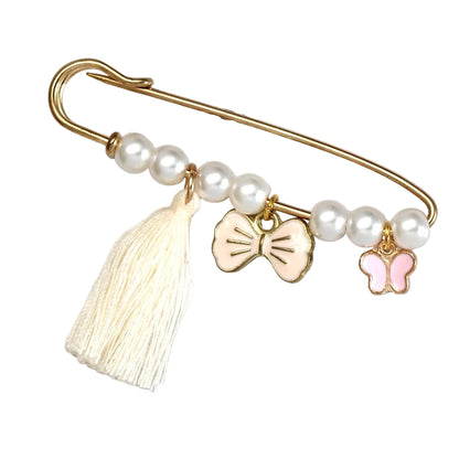 The Kiss Me Later gold evil eye pin features white pearls, a cream tassel, and two charms—a pale pink bow and a pink butterfly. This decorative brooch is perfect as a baby shower gift and comes displayed on a light background.