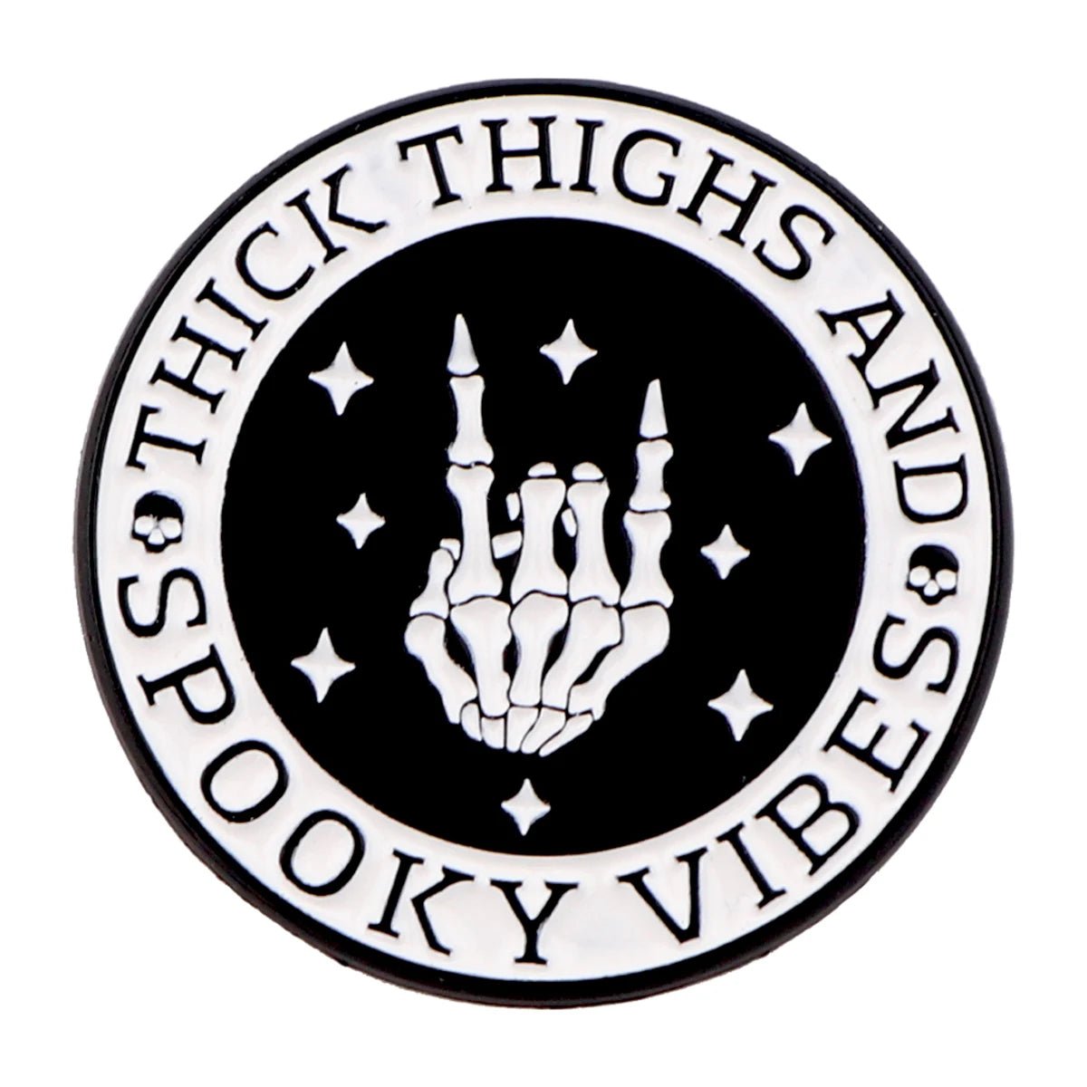 The Kiss Me Later enamel pin is a round black-and-white design with a skeleton hand rock-on gesture, stars, and the words Thick Thighs and Spooky Vibes circling the edge for an extra dose of spooky style.