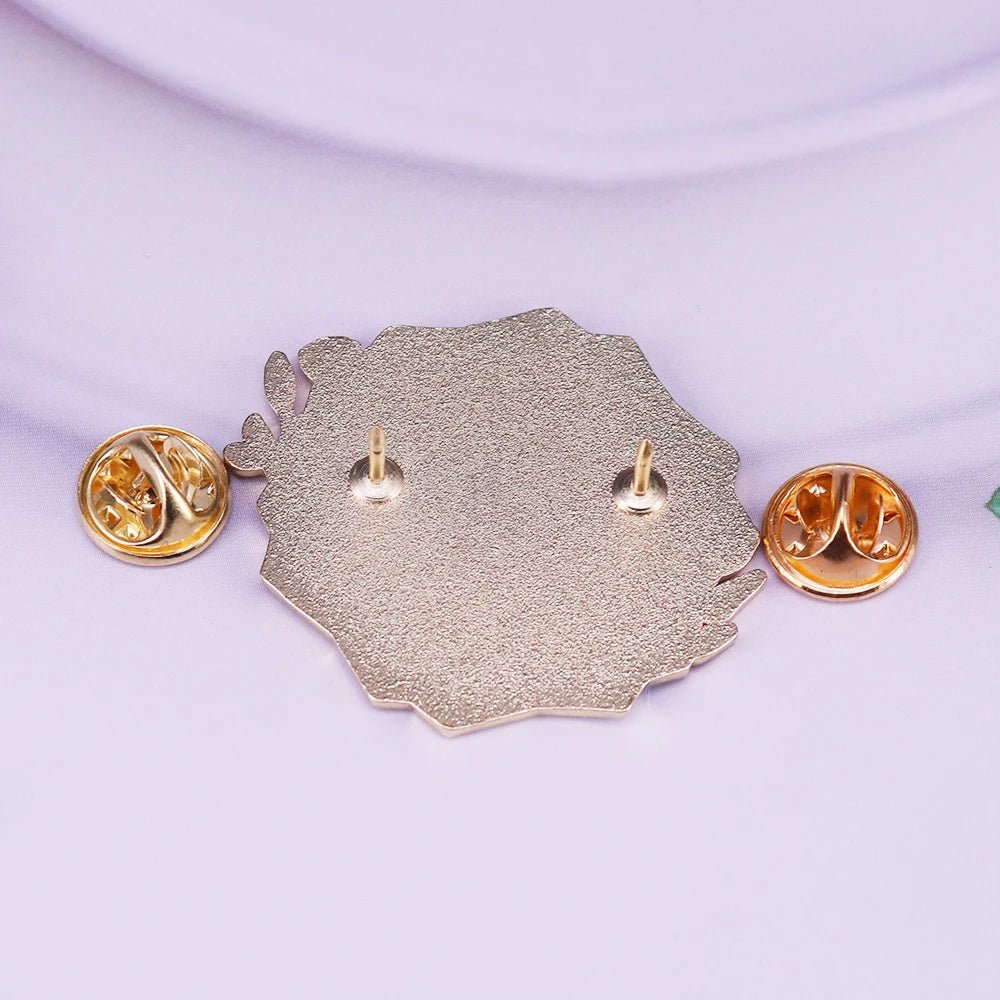 Enamel pin features a textured, irregular metal heart with two pin posts and gold butterfly backs, displayed on a soft lilac surface—symbolizing a shattered heart that heals.