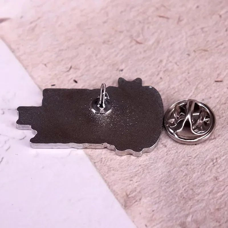 Gothic spider pin with a butterfly clasp backing, displayed face down on a textured surface. The uniquely shaped pin features a single pointed post for fastening.
