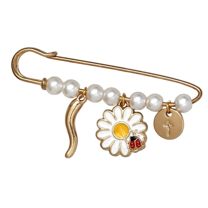 A Kiss Me Later gold safety pin brooch adorned with white pearls, beads, a gold daisy charm featuring a ladybug, and a round gold cross charm—an ideal stylish baby shower gift.