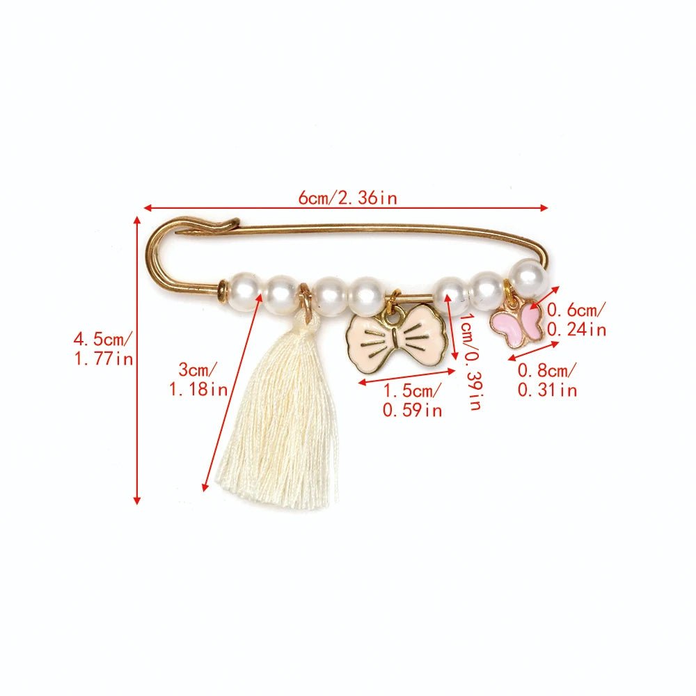 The Kiss Me Later gold safety pin brooch features white beads, a cream tassel, a bow charm, and a butterfly charm—perfect for baby showers. Red arrows and labels show each elements size in inches and centimeters.