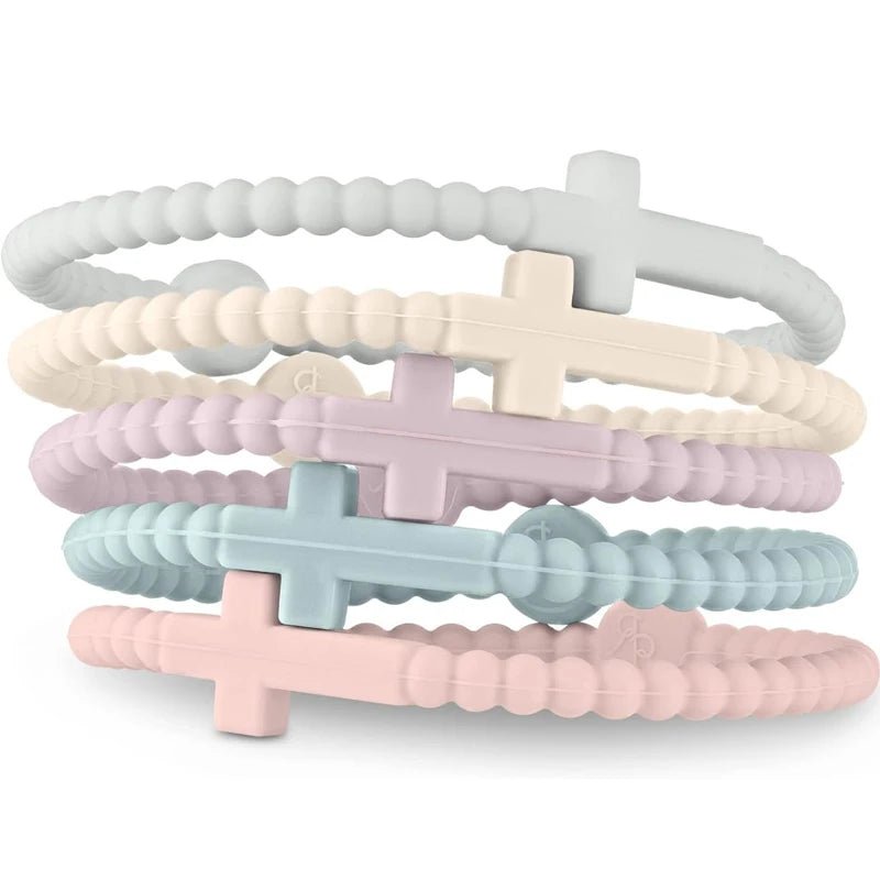 Four pastel beaded silicone Cutie Bracelets by Kiss Me Later—white, cream, lavender, and pink—each feature a cross charm at the center and stack together to celebrate Jesus with style.