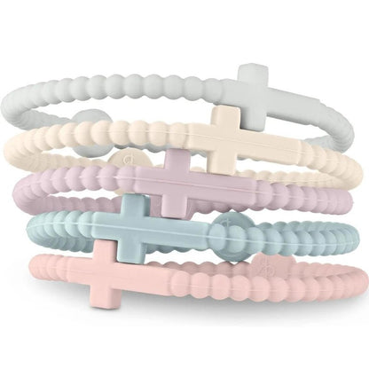 Four pastel beaded silicone Cutie Bracelets by Kiss Me Later—white, cream, lavender, and pink—each feature a cross charm at the center and stack together to celebrate Jesus with style.