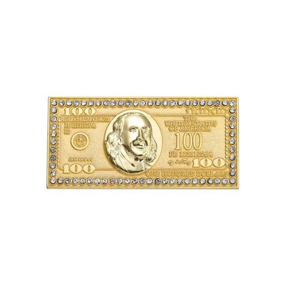 A gold-tone rectangular pin shaped like a $100 bill with a raised portrait, engraved details, and clear rhinestone border—perfect to pair with your favorite Red Lips Cash Roll for a bold statement.