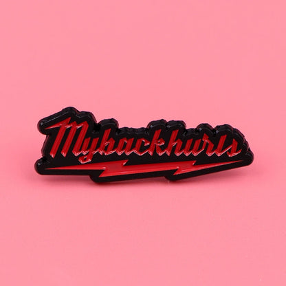 A My Back Hurts enamel pin features Mybackhurts in red script with a black outline, a red lightning bolt below, and a pink background—a bold accessory for statement style.