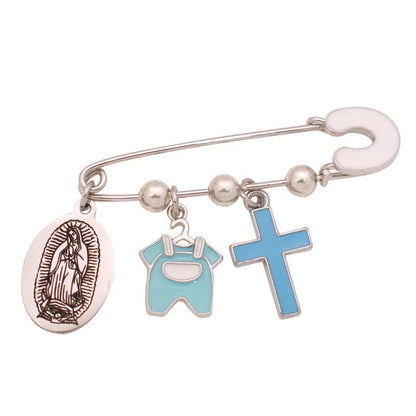 A silver Christian baby pin by Kiss Me Later features three charms: a Virgin Mary medallion, a blue baby onesie, and a blue enamel cross.