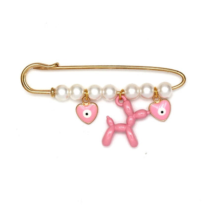 The Kiss Me Later gold safety pin brooch features white pearls and three dangling charms—two pink heart-shaped charms with eyes and a central pink balloon dog—making it a whimsical, charming gift for baby showers.