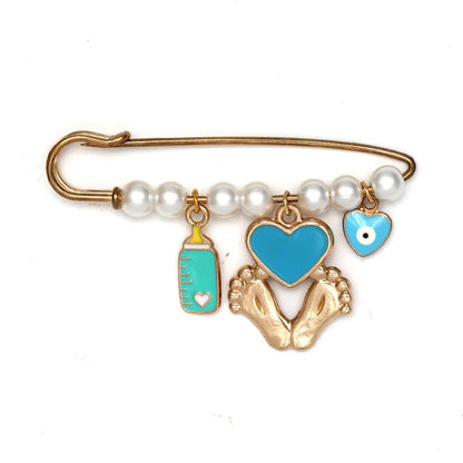 The Kiss Me Later gold safety evil eye pin features white beads and four charms—a baby bottle, a heart, baby feet, and a blue heart with a white evil eye—making it a unique gift for baby showers.