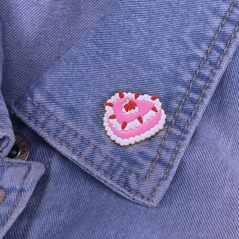 The My Cutesy Era strawberry cake enamel pin, shaped like a slice of cake with cream and strawberries, adds playful vintage charm to any blue denim jacket—perfect for anyone who loves cute accessories.