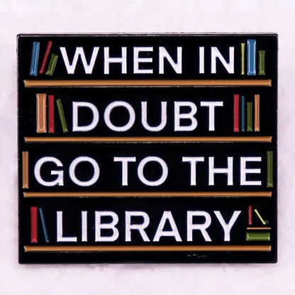 Enamel pin shows white text on black—WHEN IN DOUBT GO TO THE LIBRARY—with colorful books along the edges, ideal for book lovers and pin collectors.