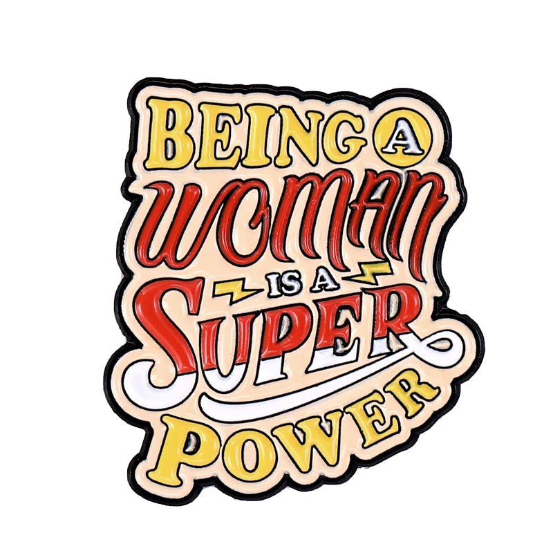 Stylized lettering reads “Being a Woman is a Super Power” in yellow, red, and white with bold outlines and a tiny heart—this enamel pin is perfect for expressing self-love.