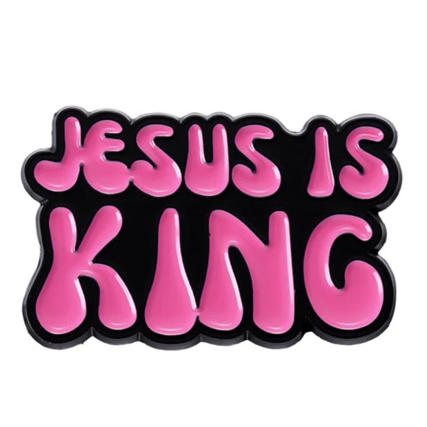 Bold, bubble-like pink letters spell JESUS IS KING on a black background, echoing the style of a vibrant pink enamel pin 