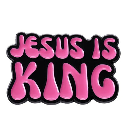 Bold, bubble-like pink letters spell JESUS IS KING on a black background, echoing the style of a vibrant pink enamel pin 