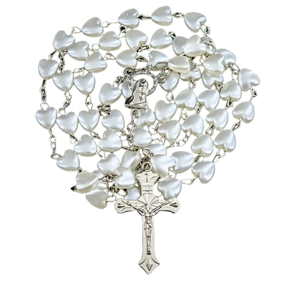My Cutesy Eras rosary necklace features white heart-shaped beads, a metal Virgin Mary centerpiece, and a detailed crucifix at the end, all beautifully arranged in a spiral.