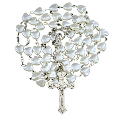 My Cutesy Eras rosary necklace features white heart-shaped beads, a metal Virgin Mary centerpiece, and a detailed crucifix at the end, all beautifully arranged in a spiral.