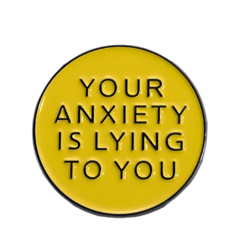 A round yellow enamel pin by My Cutesy Era features black text reading YOUR ANXIETY IS LYING TO YOU on a white background—a motivational accessory with a positive affirmation.