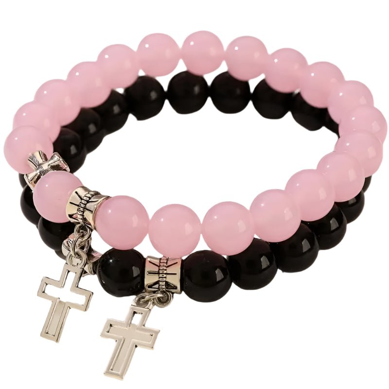 The My Cutesy Era set includes two stacked beaded crystal bracelets, one with pink and one with black beads, each featuring a silver Cross charm and spacer beads. These Christian bracelets form a stylish circular duo.