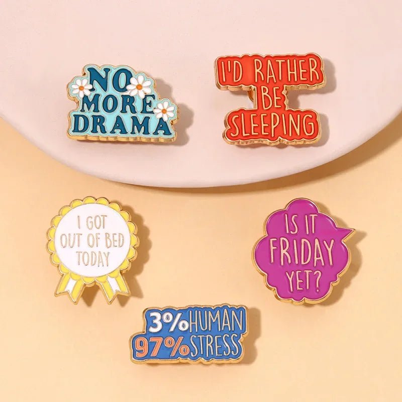 Five vibrant enamel pins including a red love heart and a playful “Cute But Psycho” design, are shown on a light surface. The set also features “NO MORE DRAMA” and “I’D RATHER BE SLEEPING.”.
