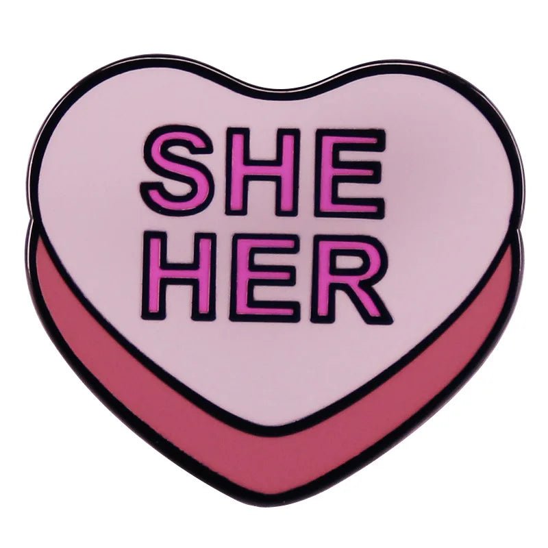 Show your pride with this My Cutesy Era heart-shaped enamel pin, featuring a light pink background, darker pink border, and bold SHE HER text in pink and purple—perfect for adding a stylish statement to your look.